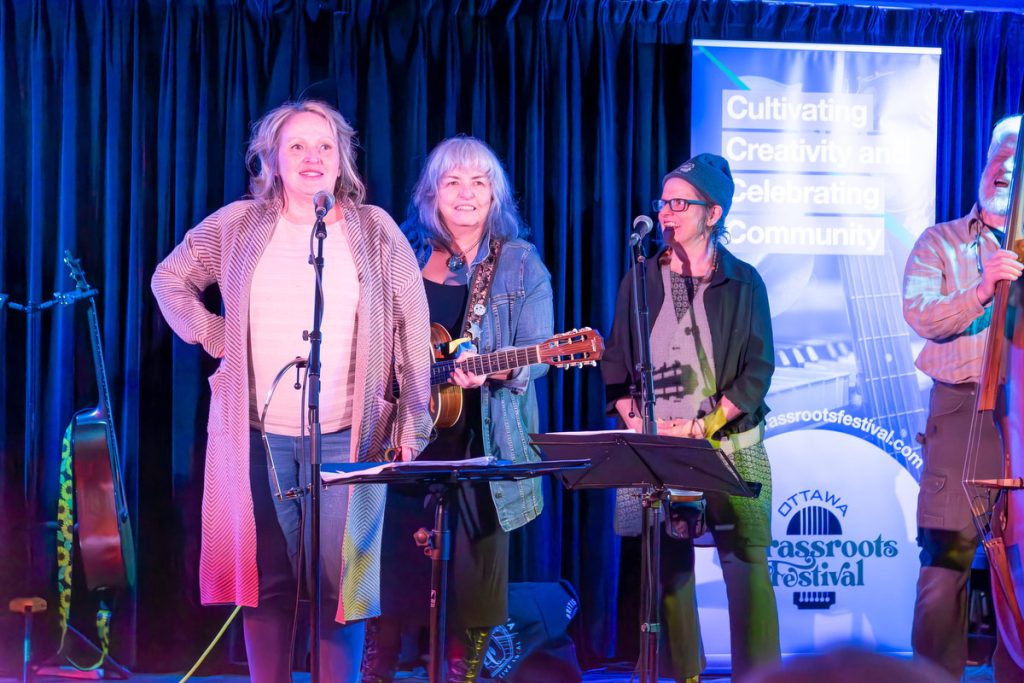 Alison Bowie speaking about the festival at Irene's, flanked by Lynn Miles and The Tumbleweeds
