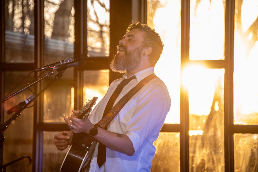 Rory Taillon singing during sunset indoors at First Unitarian Church