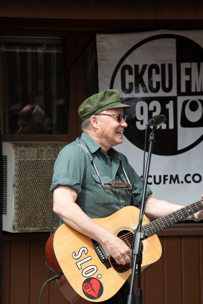 Part of a great CKCU broadcast outdoors, Slo' Tom smiles while holding his guitar